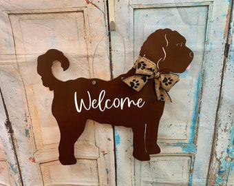 May include: A brown dog silhouette welcome sign with a brown and black paw print bow. The sign says "Welcome" in white lettering.