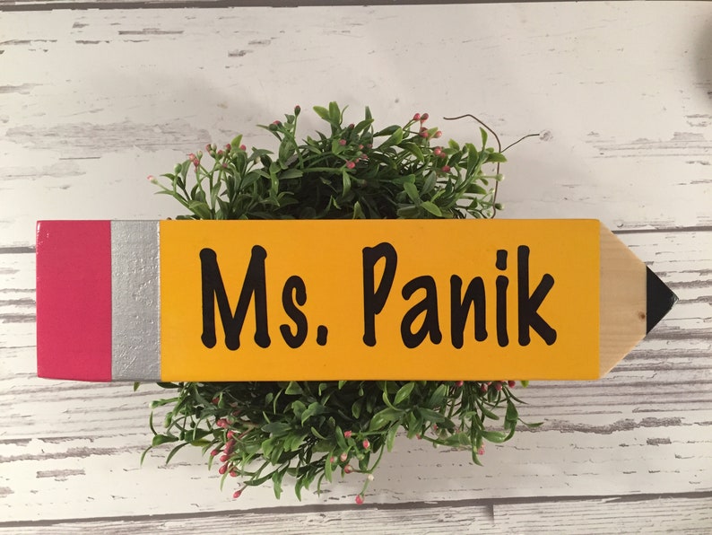 May include: A yellow wooden pencil with a red and silver eraser, painted with the text "Ms. Panik".