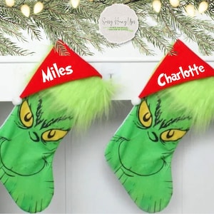 May include: Two green Grinch Christmas stockings with red Santa hats. The stockings have the names "Miles" and "Charlotte" written on the hats.