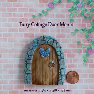 May include: A fairy cottage door mould with a wooden door, a blue butterfly, and a stone arch. The door measures 2 3/4 x 2 3/8 x 1/4 inch. The text "Fairy Cottage Door Mould" is above the door.