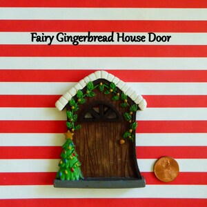 May include: A miniature fairy gingerbread house door with a Christmas tree and star. The door is brown with a white roof and green garland. The text "Fairy Gingerbread House Door" is above the door.
