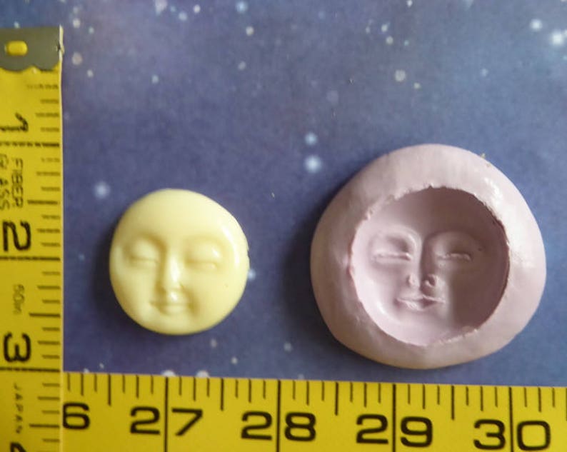 May include: A yellow, smiling moon face and a pink mold of the same face are displayed. The moon face is approximately 1 inch in diameter. A yellow measuring tape is in the image, with measurements in inches.