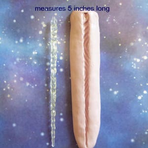 Peut inclure: L'image pr&eacute;sente deux objets sur un fond bleu parsem&eacute; de blanc. L'un est une forme de gla&ccedil;on claire et torsad&eacute;e, l'autre est une forme rose allong&eacute;e avec une rainure centrale. Le texte de l'image indique "mesure 5 pouces de long", soit environ 12,7 cm.