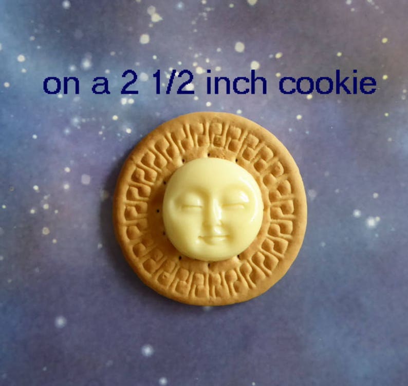 May include: A round, tan cookie with a cream-colored sun-shaped decoration. The cookie is approximately 2.5 inches in diameter. The text "on a 2 1/2 inch cookie" is written above the cookie against a blue background.