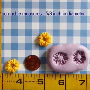 May include: Yellow scrunchies, each approximately 0.625 inches in diameter, are displayed with a penny and a lilac-colored mold. The text reads "scrunchie measures: 5/8 inch in diameter". The items are on a blue and white checkered background.