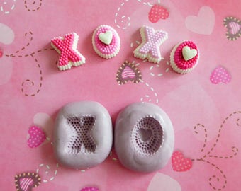May include: Pink and white XOXO Valentine's Day-themed decorations and molds. The decorations include the letters X and O, with a beaded texture and heart accents. The molds are in the shape of the letters X and O.