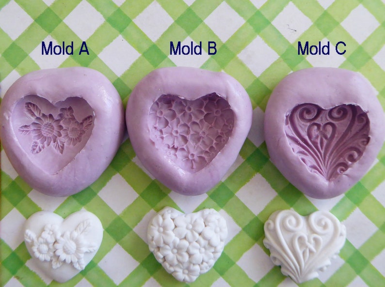 May include: Three heart-shaped silicone molds in lavender, each with a different embossed design: flowers, small blossoms, and a swirling pattern. Below, three white heart-shaped castings showcase the mold designs. The text "Mold A", "Mold B", and "Mold C" are visible.