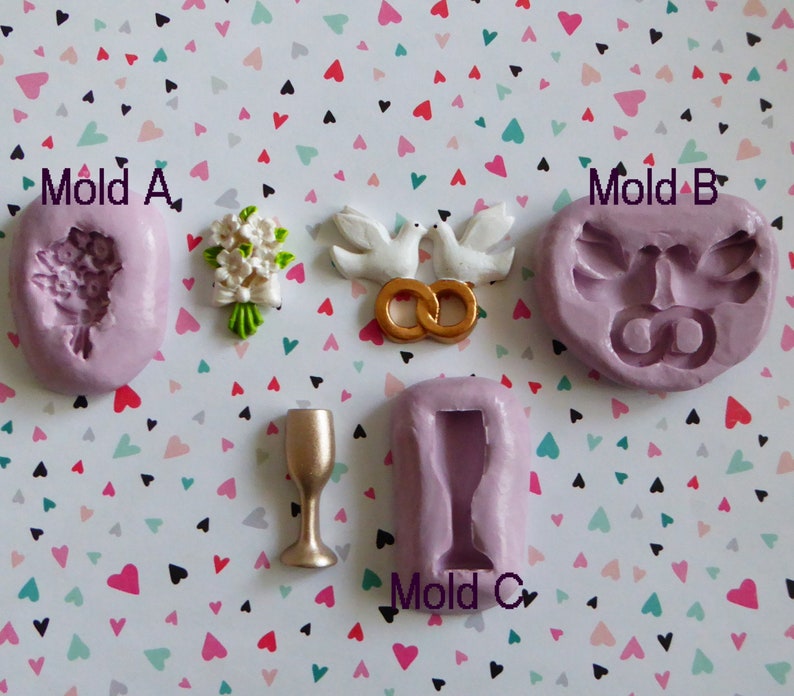 May include: A collection of wedding-themed molds and decorations. Includes a bouquet, doves with gold rings, and a champagne glass. The molds are lavender, and the decorations are white, green, and gold. The text "Mold A", "Mold B", and "Mold C" is visible.