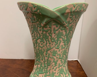 May include: A green and pink ceramic vase with a unique, splatter-like design. The vase has a wide mouth and a narrow base.