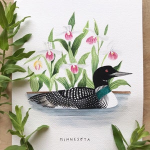May include: Watercolor painting of a loon swimming in a lake with pink and white lady slipper orchids in the background. The painting is signed "Minnesota".