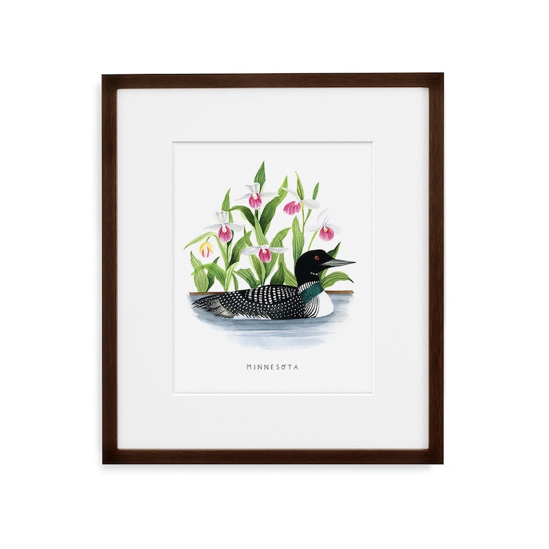 May include: A framed print of a watercolor painting depicting a loon swimming in a lake with pink and white lady slipper orchids. The text "Minnesota" is printed below the image.