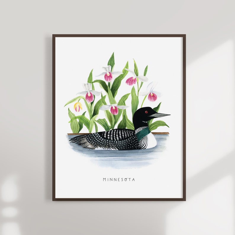 May include: A watercolor painting of a loon swimming in a lake with white and pink lady slipper orchids in the background. The painting is framed and has the word "MINNESOTA" written at the bottom.