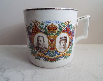 Antiek koffieblikje. Britse koninklijke familiememorabilia. Witte koffiemok koninklijke herdenkingsmunt, 1935 koning George V en koningin Mary zilveren jubileum