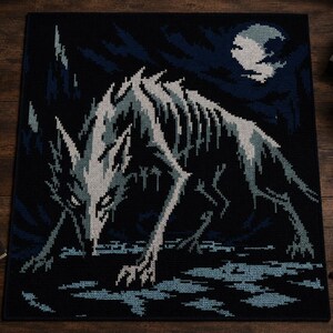以下が含まれることがあります： 黒と青のラグで、満月の下で骨格のオオカミのピクセル化された画像が特徴です。オオカミは主に白とグレーで、背景と水に青のアクセントがあります。ラグはゴシックまたはファンタジーをテーマにしています。