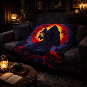 May include: A dark blue knitted throw blanket featuring a hooded figure holding a lantern against a red and yellow moon. The blanket has a spooky, Halloween theme and is draped over a dark gray sofa. The scene is lit by a warm, inviting glow.