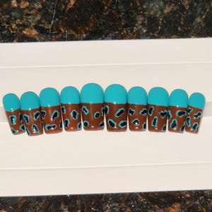 May include: Set of ten turquoise and brown press-on nails with a leopard print design.
