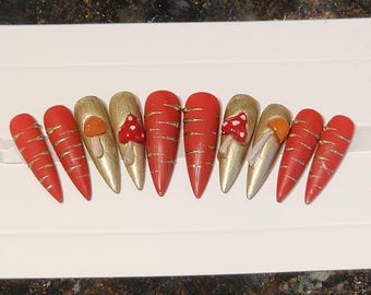 Unghie finte a tema bosco stravagante: unghie a stiletto realizzate a mano con decorazioni a forma di fungo.