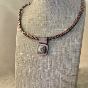 May include: A copper necklace with a twisted chain and a square pendant featuring a green and white stone.
