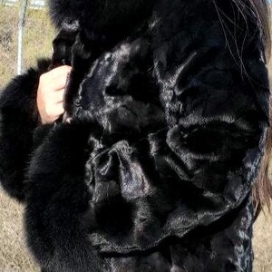 May include: A black fur coat with a large collar and cuffs. The coat is made of a soft, luxurious fur and has a classic, elegant style.