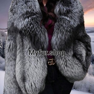 May include: A silver fox fur coat with a large collar. The coat is made of soft, luxurious fur and has a sleek, stylish design. The fur is a beautiful silver colour with black tips.