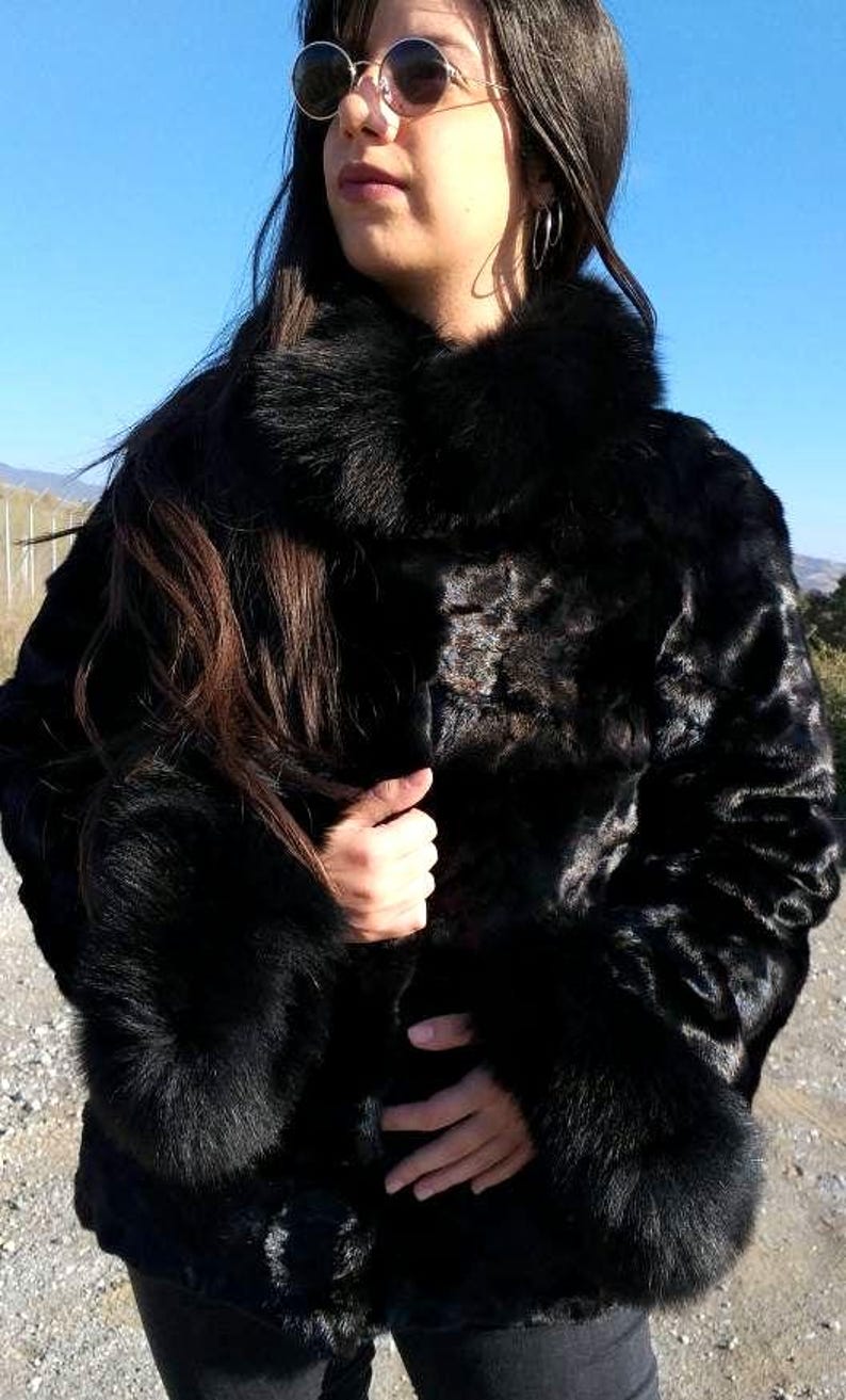 May include: A black fur coat with a large collar and cuffs. The coat is made of a soft, luxurious fur and has a sleek, modern design.