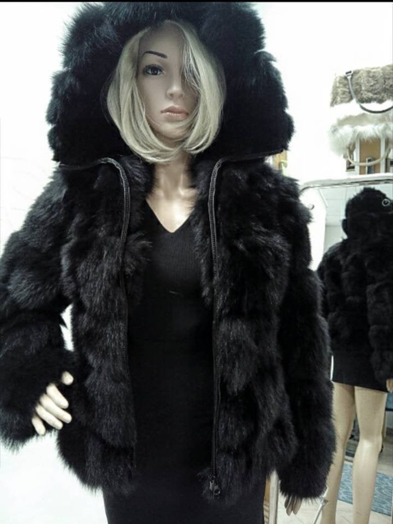 May include: A black faux fur jacket with a zipper closure and a large hood. The jacket has a layered look with multiple rows of fur.
