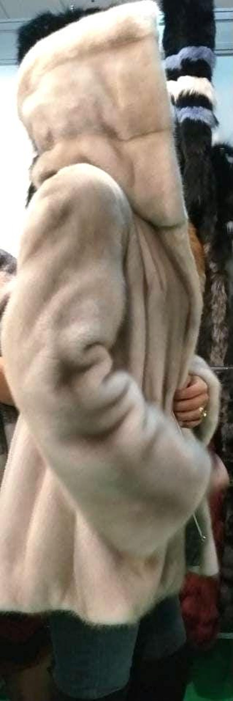 May include: A white fur coat with a hood. The coat is made of soft, luxurious fur and has a classic design.