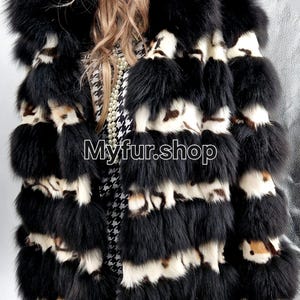 May include: A luxurious black and white fur coat with a striking pattern. The coat features horizontal bands of black fur alternating with sections of white and brown patterned fur. The text "Myfur.shop" is visible.