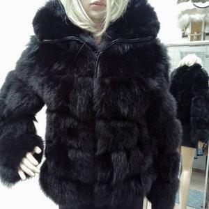 May include: A black faux fur jacket with a zipper closure and a hood. The jacket has a quilted design and is made of soft, plush fur.