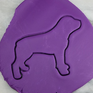 K&ouml;nnte beinhalten: Lilafarbener Fondant mit einem eingepressten Keksausstecher in Form eines Hundes.
