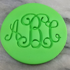 May include: A green silicone mould for baking cookies with a monogram design of the letters A, B, and L.