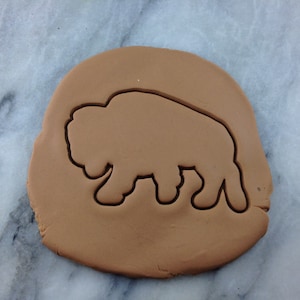 May include: Brown cookie dough with a cutout of a bison silhouette.