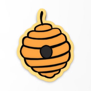 May include: A yellow and black beehive cookie cutter with a rounded shape and a small hole in the center.