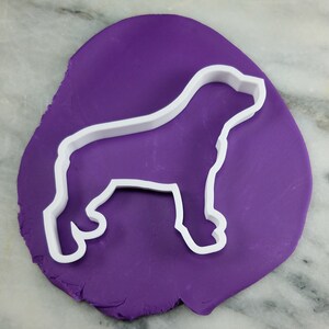 K&ouml;nnte beinhalten: Ein wei&szlig;er Plastik-Ausstecher in Form einer Hundesilhouette auf einem violetten Hintergrund.