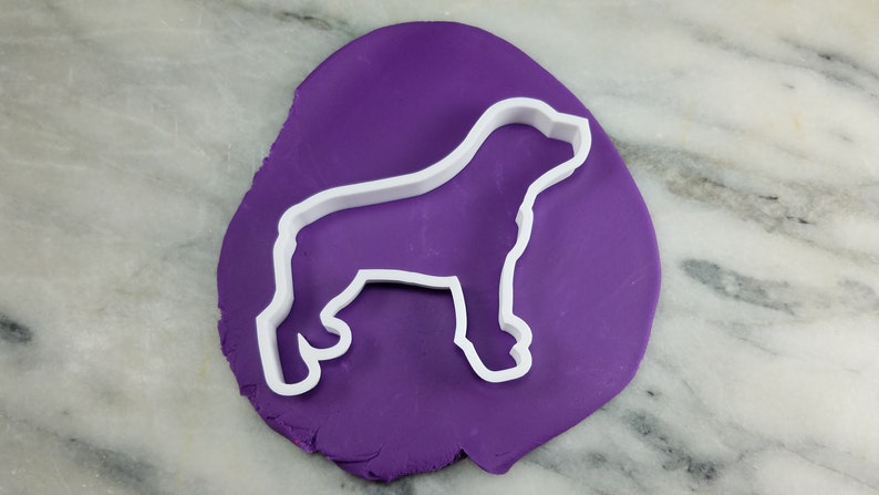 K&ouml;nnte beinhalten: Ein wei&szlig;er Plastik-Ausstecher in Form einer Hundesilhouette auf einem violetten Hintergrund.