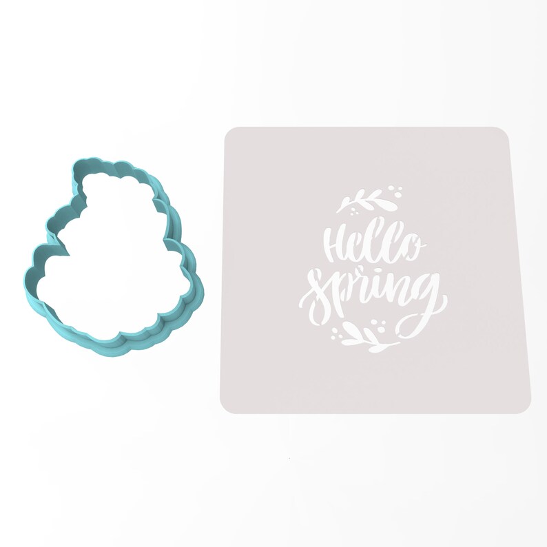 Op de afbeelding: Een lichtblauwe koekjesvormer in de vorm van een wolk met de woorden "Hello Spring" in een witte sjabloon op een grijze achtergrond.