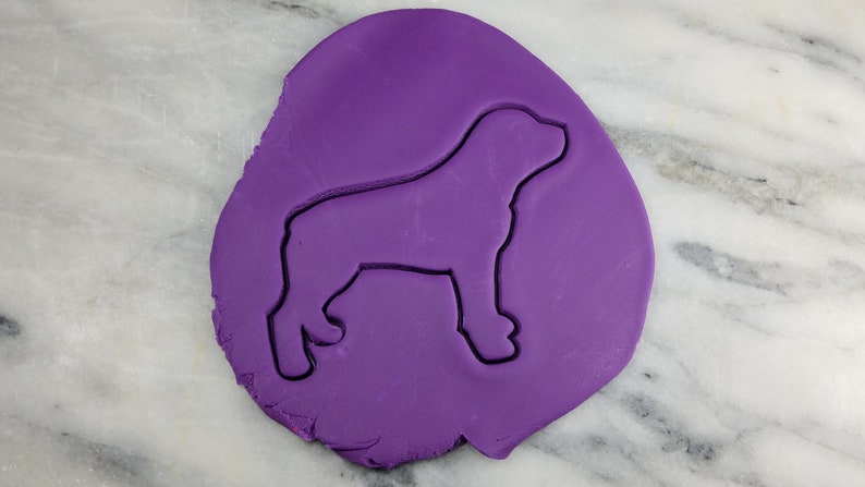 K&ouml;nnte beinhalten: Lilafarbener Fondant mit einem eingepressten Keksausstecher in Form eines Hundes.