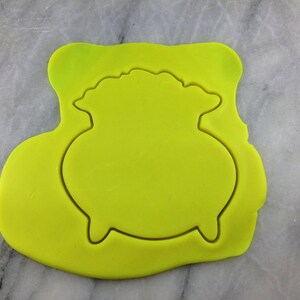 May include: A yellow silicone mold for baking a cauldron shaped cookie or cake.