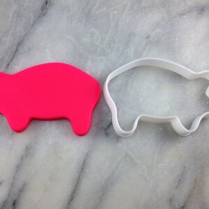 May include: A pink pig cookie cutter and a white plastic pig cookie cutter.