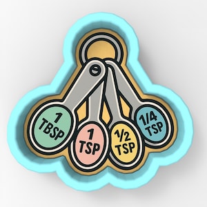 Puede incluir: Un cortador de galletas azul claro con forma de cucharas medidoras. Las cucharas están etiquetadas como 1 cucharada, 1 cucharadita, 1/2 cucharadita y 1/4 cucharadita. Las cucharas son plateadas con etiquetas coloridas y un borde dorado.