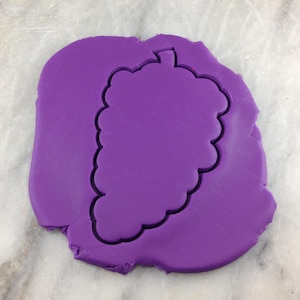 May include: Purple fondant with a grape-shaped cookie cutter pressed into it.