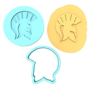Puede incluir: Un conjunto de tres cortadores de galletas con forma de casco espartano. Los cortadores están hechos de plástico azul y se muestran sobre un fondo blanco.