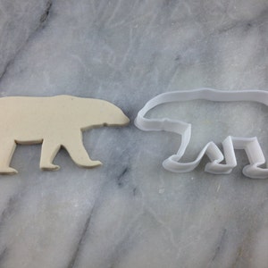 May include: A white plastic polar bear cookie cutter and a white fondant polar bear cookie.