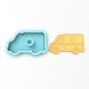 May include: A light blue plastic cookie cutter shaped like an ambulance, next to a yellow cookie cut out in the shape of an ambulance.