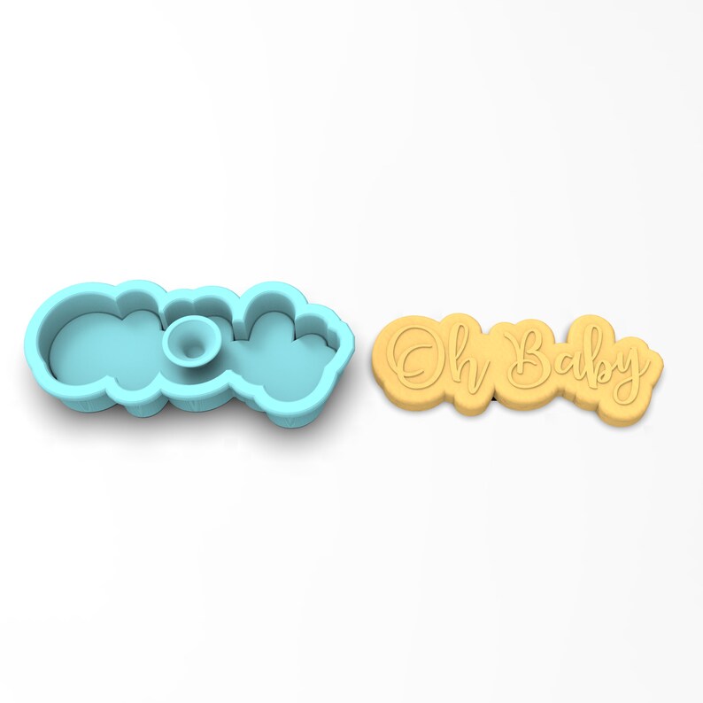 May include: A blue plastic cookie cutter shaped like the words "Oh Baby" and a yellow cookie with the same words imprinted on it.