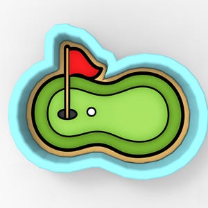 May include: A golf-themed cookie cutter featuring a green putting green with a red flag, a white golf ball, and a black hole. The cutter has a light blue border and a brown outline.