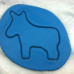 Peut inclure: Une découpe de fondant bleu en forme d'âne, une forme traditionnelle de piñata mexicaine, sur une surface blanche.
