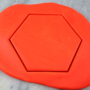 Puede incluir: Fondant naranja con un corte hexagonal.