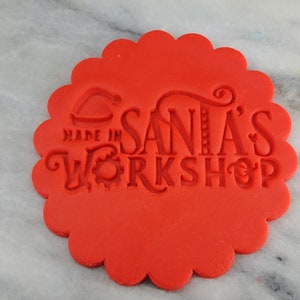 May include: Red round cookie cutter with a scalloped edge. The cutter is imprinted with the text "Made in Santa's Workshop".