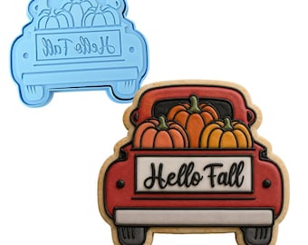 Può includere: Un tagliabiscotti in plastica azzurra a forma di camion che trasporta zucche e un biscotto decorato a forma di camion rosso che trasporta tre zucche arancioni con la scritta Hello Fall in corsivo nero sul portellone posteriore.